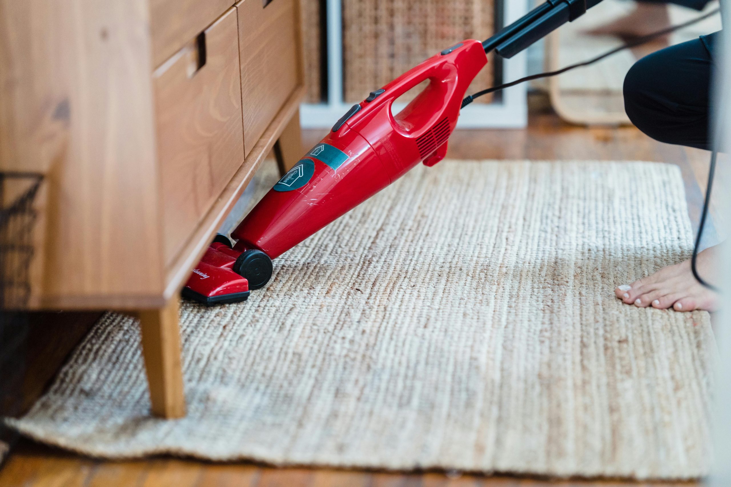 cleaning carpet with a red lightweight vacuum cleaner